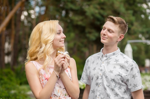 Photo jeune fille blonde charmante flirte et avec un gars dans le jardin.