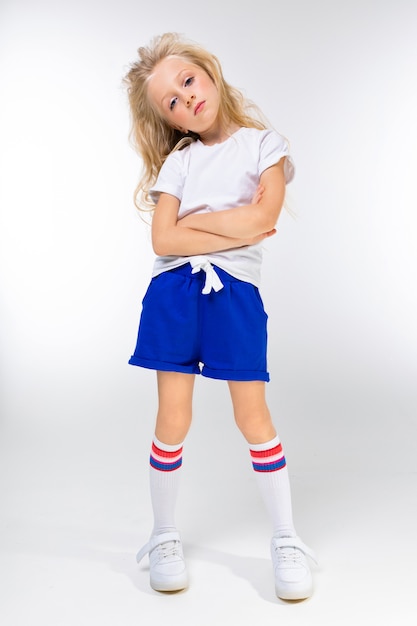 Jeune fille blonde charmante Sportswear avec les bras croisés sur un mur blanc wal