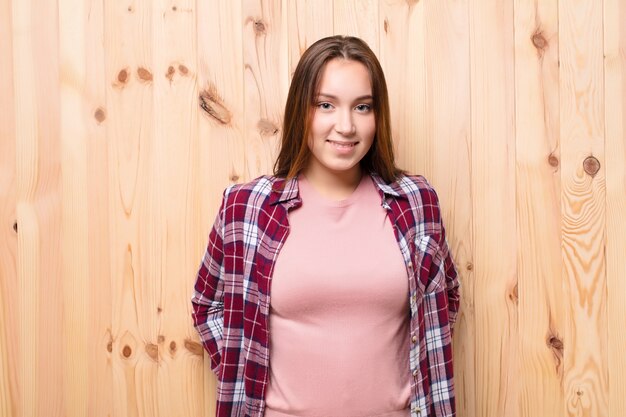 Jeune fille blonde contre un mur en bois