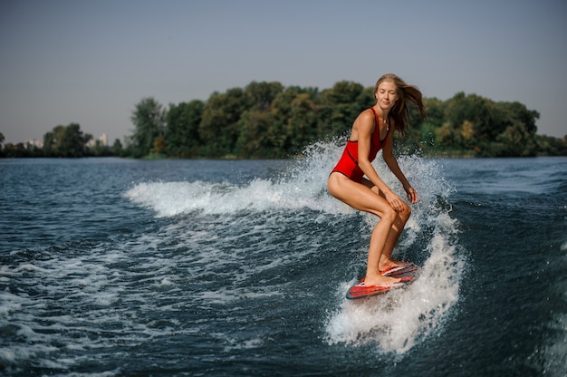 Jeune fille blonde debout sur le wakeboard rouge