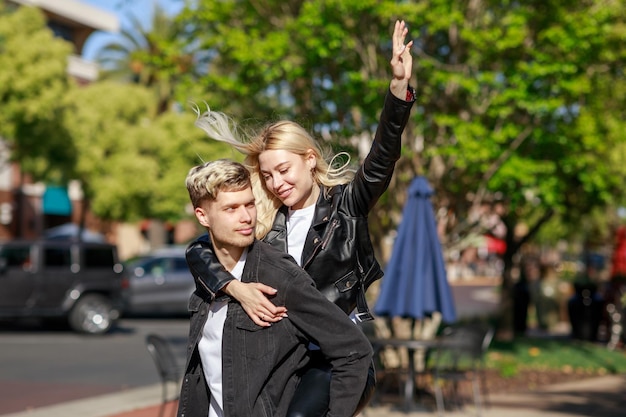 Jeune fille blonde sur le dos de son petit ami et lève son doigt en l'air Photo de haute qualité