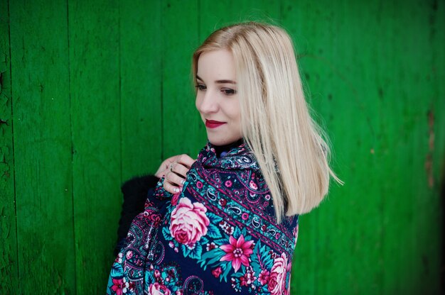 Jeune fille blonde avec une écharpe brodée à la main posée le jour de l'hiver.