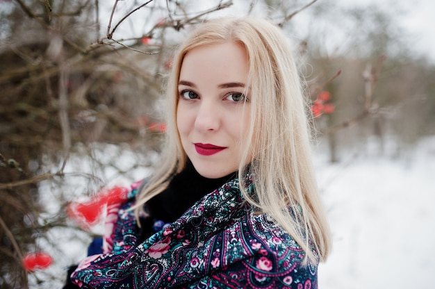Jeune fille blonde avec une écharpe brodée à la main posée le jour de l'hiver.