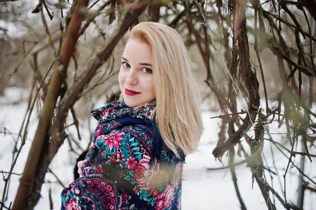 Jeune fille blonde avec une écharpe brodée à la main posée le jour de l'hiver.