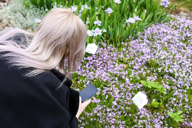 Jeune fille blonde faisant une photo dans un parc de printemps