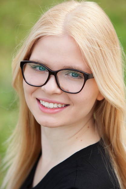 Jeune fille blonde avec des lunettes en souriant