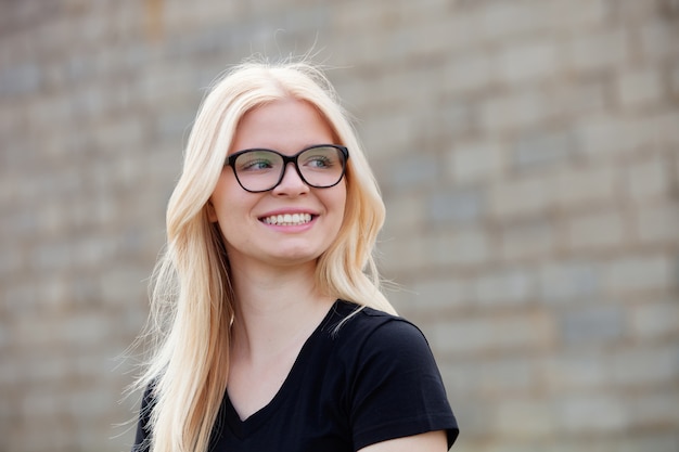 Jeune fille blonde avec des lunettes en souriant