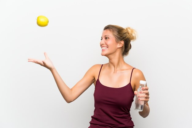 Jeune fille blonde avec une pomme et une bouteille d'eau