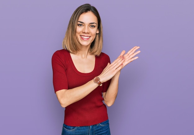 Jeune fille blonde portant des vêtements décontractés applaudissant et applaudissant heureux et joyeux sourire fier mains ensemble