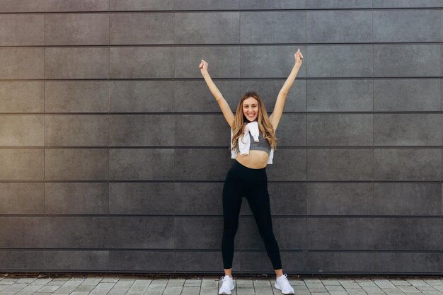 Jeune fille blonde portant des vêtements de sport célébrant la folie et la folie du succès avec les bras levés et hurlant l'espace de copie du concept gagnant excité