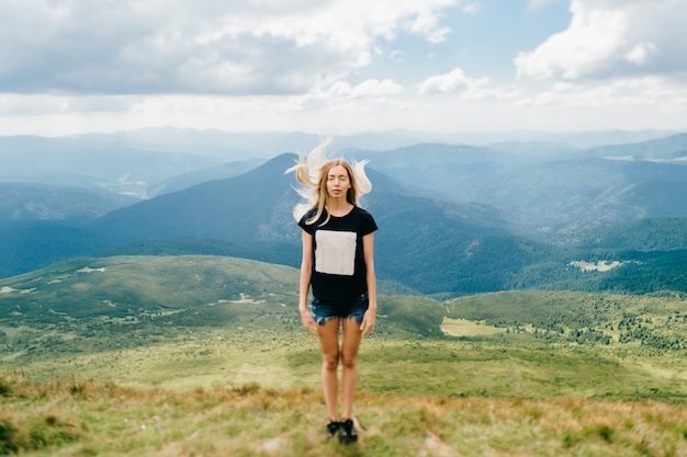 Jeune fille blonde posant dans les montagnes