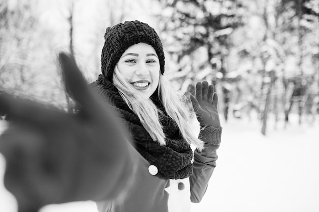 Jeune fille blonde en pull rouge écharpe, bonnet et santas posant au parc le jour de l'hiver.