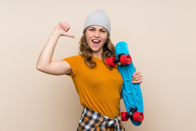 Jeune fille blonde skateur fière d'elle-même sur un mur isolé