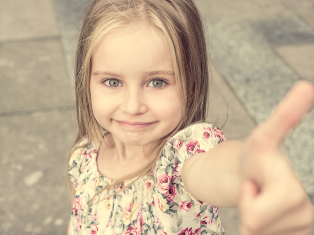 Jeune fille blonde souriant timidement