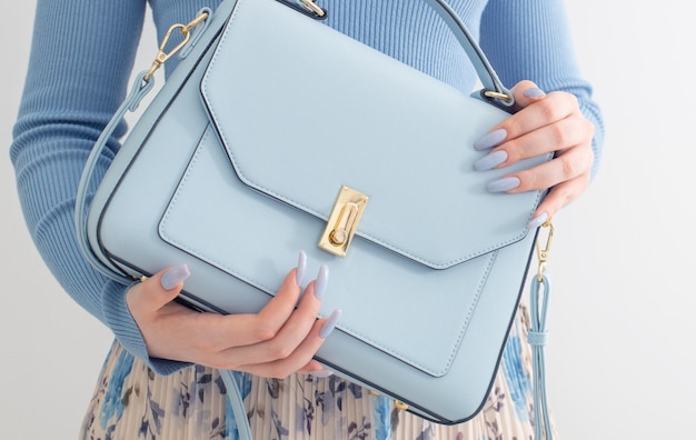 Jeune fille en blouse bleue et jupe plissée avec sac à main bleu sur fond blanc