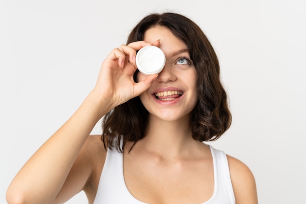 Jeune fille avec boîte de crème hydratante isolé sur blanc