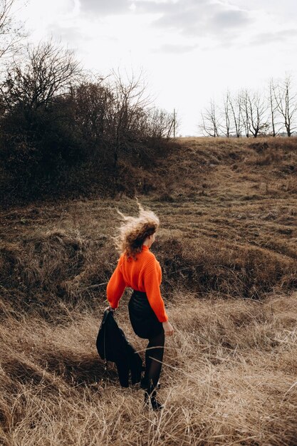 Photo une jeune fille bouclée dans un pull orange sur le fond de la nature d'automne