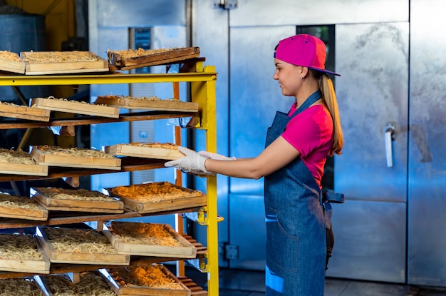 Jeune fille de boulangerie travaillant à l'usine. Grand panier de baguette en usine.