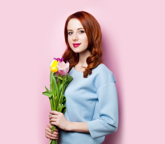 Jeune fille avec bouquet de tulipes sur rose