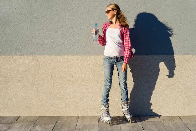 Jeune fille avec une bouteille d'eau, chaussée de rouleaux