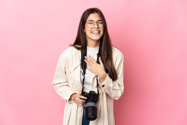 Jeune fille brésilienne photographe isolée sur mur rose souriant beaucoup