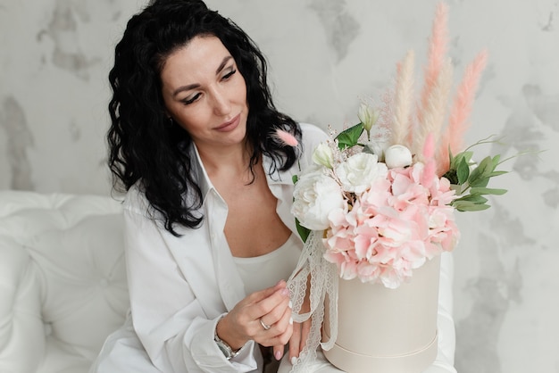 Jeune fille brune aux cheveux bouclés avec un bouquet de fleurs