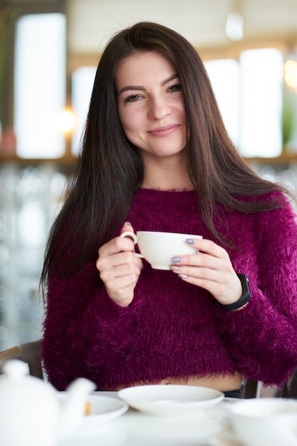 Jeune fille brune blanche buvant du thé au café et souriant