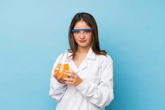 Jeune fille brune sur bleu isolé avec un tube à essai scientifique