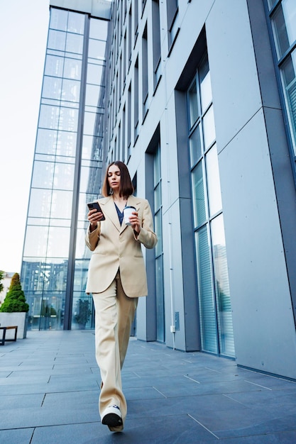 Une jeune fille brune dans le contexte d'un centre d'affaires office center En déplacement, il lit les nouvelles de son smartphone