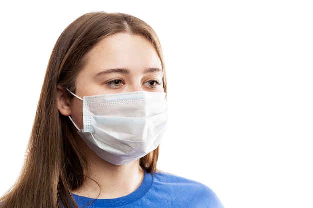 Jeune fille brune dans un masque. Pandémie de coronavirus et allergies saisonnières. Isolé sur un mur blanc. Fermer.