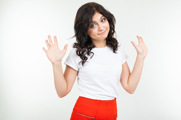 Jeune fille brune dans un t-shirt blanc s'inquiète d'un problème sur un fond de studio blanc.