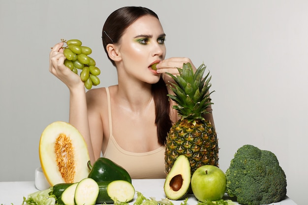 jeune fille brune avec du maquillage manger des raisins