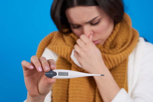 Jeune fille brune a froid prenant la température