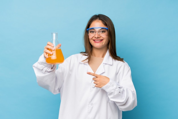 Jeune fille brune isolée avec un tube à essai scientifique et en le pointant