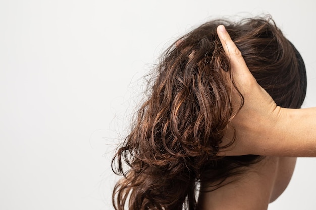 Jeune fille brune jouant avec ses cheveux ondulés Concept de routine quotidienne de soins capillaires