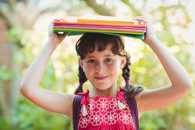 Jeune fille brune avec des livres sur la tête