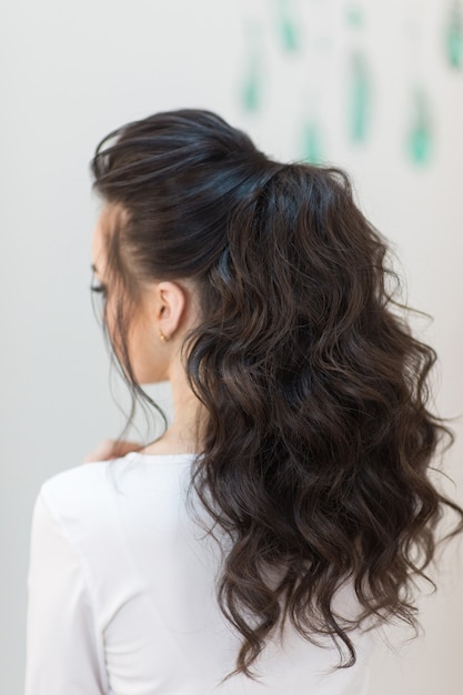 Jeune fille brune avec un look de coiffure à la mode de l'arrière