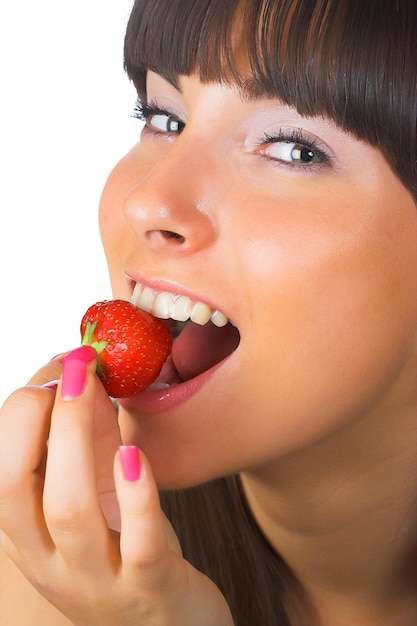Jeune fille brune mange une fraise