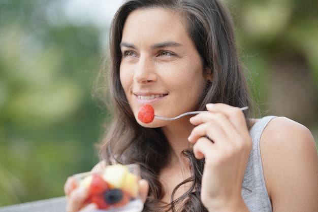 Jeune fille brune mangeant des fruits frais