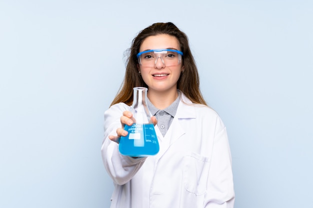 Jeune fille brune sur un mur bleu isolé avec un tube à essai scientifique