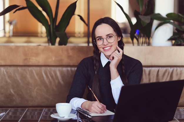 Jeune fille brune avec des nattes portant des lunettes d'apprentissage à l'intérieur du café