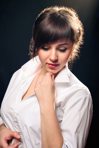 Jeune fille brune en posant une chemise blanche