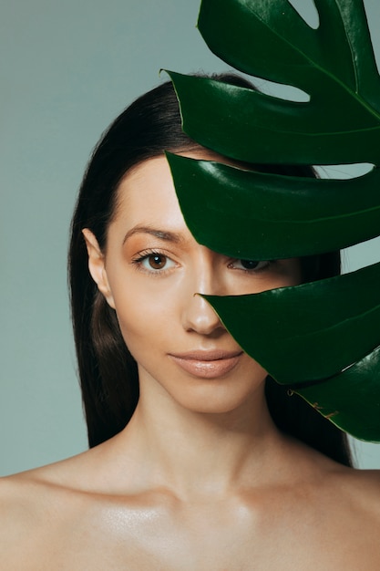 Photo jeune fille brune posant avec des feuilles exotiques