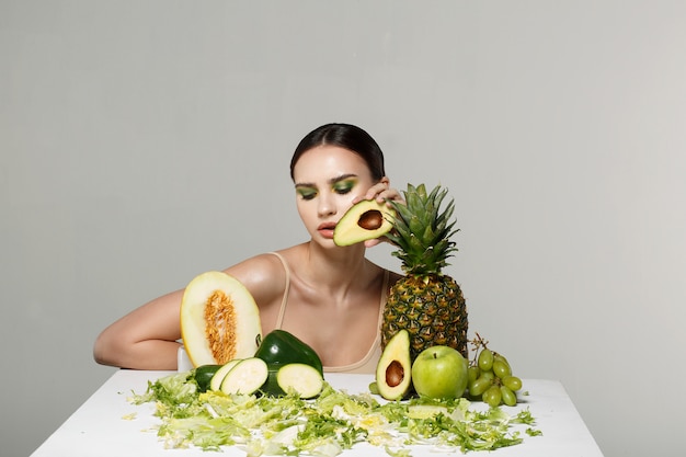 jeune fille brune posant avec table de fruits et légumes