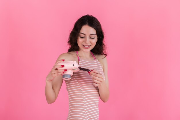 Jeune fille brune regarde une photo prise sur un appareil photo instantané