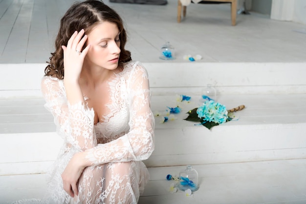 Jeune fille brune en robe blanche assise sur les escaliers