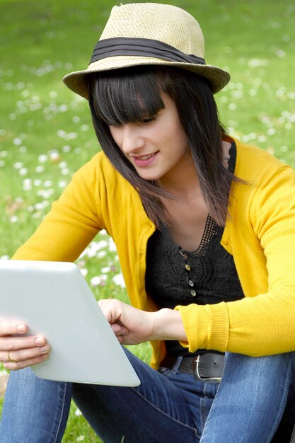 Jeune fille brune avec une tablette dans le parc, à l'extérieur