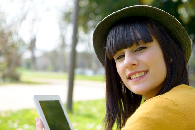 Jeune fille brune avec une tablette dans le parc, à l'extérieur