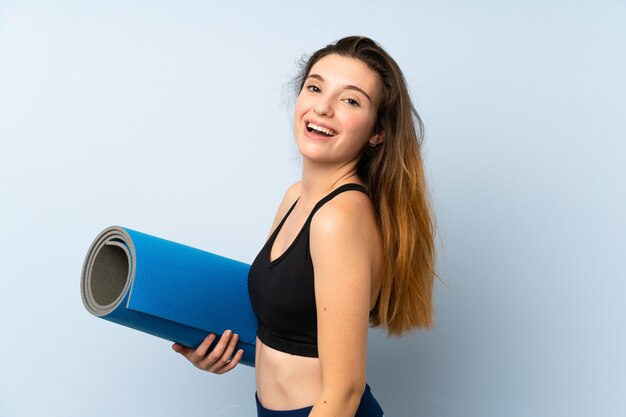 Jeune fille brune avec tapis sur mur isolé