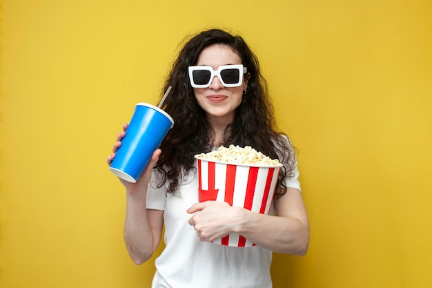 jeune fille brune téléspectatrice en lunettes 3d et t-shirt blanc tient un grand seau de pop-corn